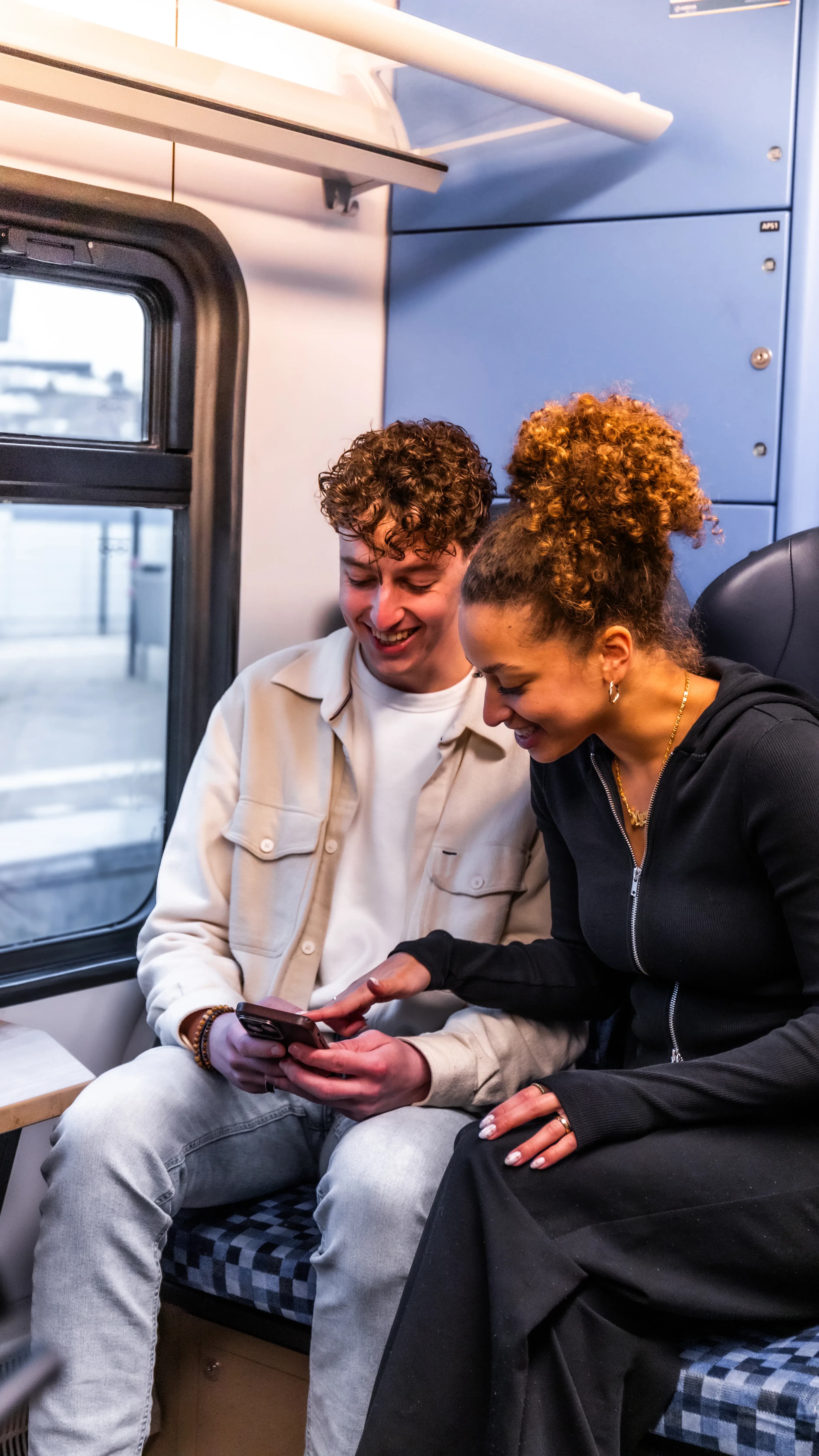 Twee jonge mensen samen in de trein Koop je treinkaartje makkelijk met reisapp glimble. Geen OV-chipkaart nodig.
